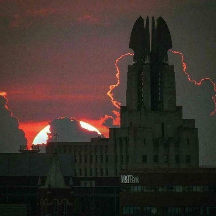 Dark, imposing building against a fiery sunset, appearing as a fortress for an evil mastermind to conquer the world.