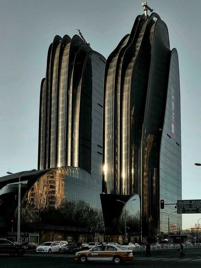 Two dark, wavy modern buildings with reflective surfaces, a dramatic setting for an evil mastermind.