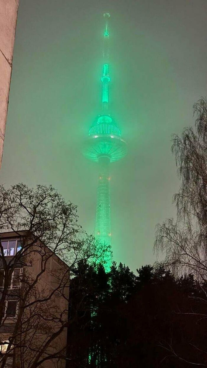 A towering structure glowing green in the fog, resembling an evil mastermind's building.