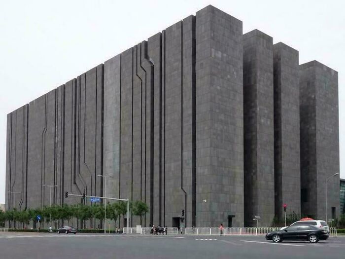 A massive, dark, monolithic building with intricate vertical lines, appearing as an evil mastermind's headquarters.