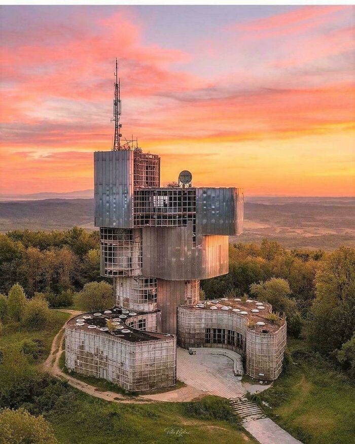 An abandoned, brutalist communication tower on a hill during sunset, ideal for an evil mastermind's plan.