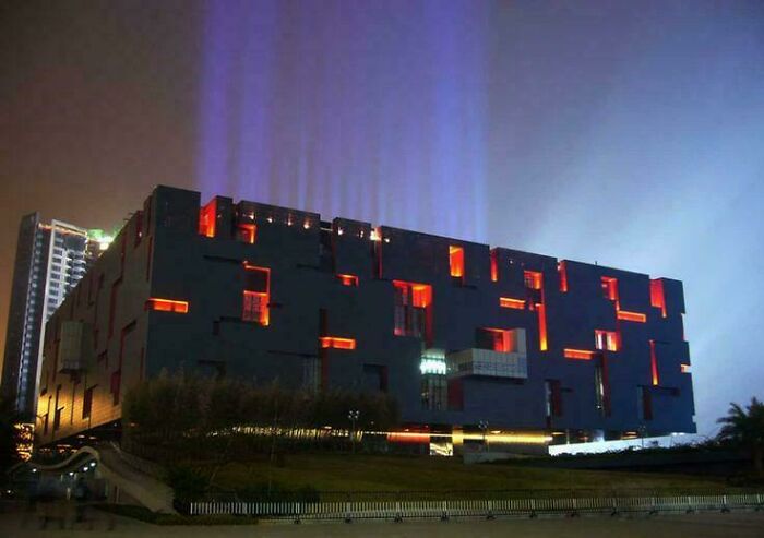 A dark, modern building with glowing red windows and purple light beams, perfect for an evil mastermind.