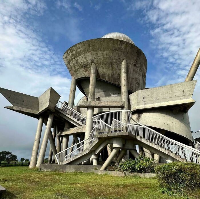 A futuristic, brutalist concrete building with an observatory dome, perfect for an evil mastermind's global domination.