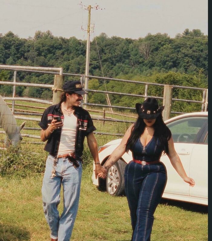 A couple walking in a field, the woman displaying an unnatural waistline for social media.