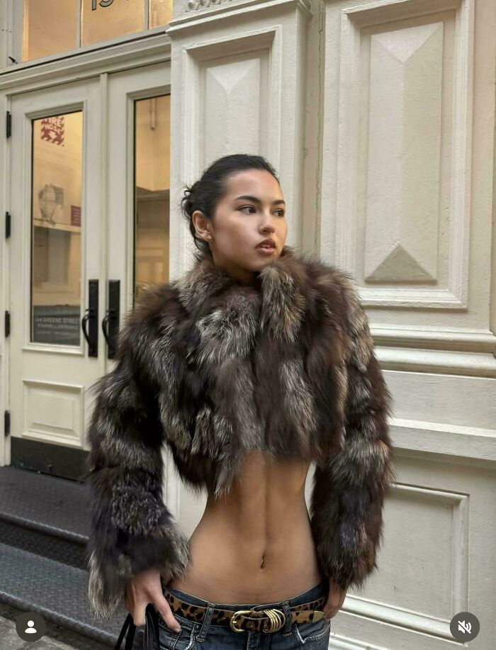 Woman in a cropped fur jacket with an unnatural pose on social media.