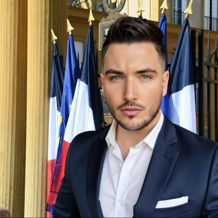 A man posing unnaturally for social media, standing in front of flags in a formal setting, with an overly smooth appearance.