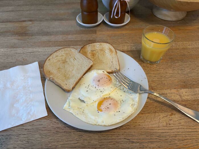 A plate of two sunny-side-up eggs, two pieces of toast, and a glass of orange juice, symbolizing a great dad's care.