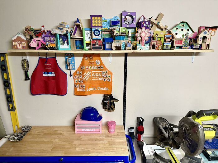 A workshop shelf filled with colorful wooden crafts and two aprons, showcasing a great dad's creative space.