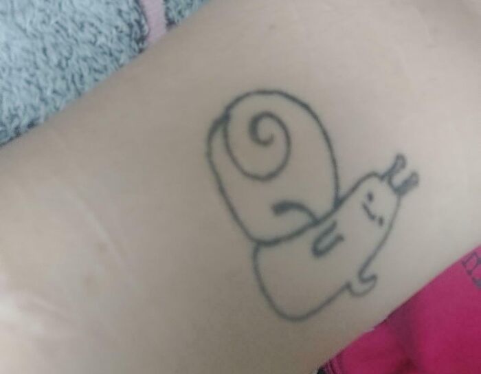 Simple black outline tattoo of a snail on skin, an example of bad tattoos showing thinking first is optional moments.