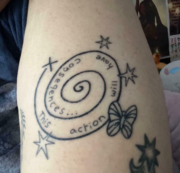 Black ink spiral tattoo with stars, a butterfly, and a misspelled quote showing bad tattoos and design mistakes.