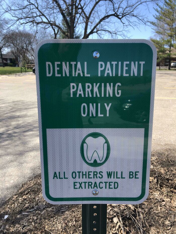 Green parking sign for dental patients with a tooth symbol and warning all others will be extracted, a bizarre sign.
