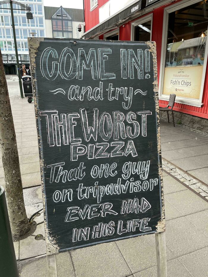 Humorous chalkboard sign inviting people to try the worst pizza according to one TripAdvisor review.
