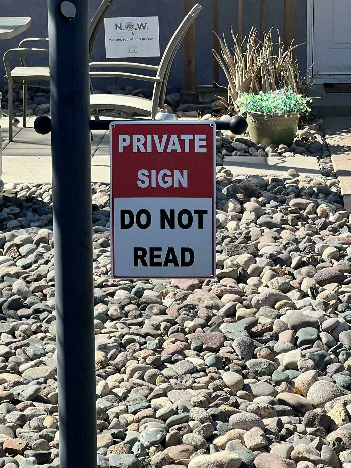 Absurd private sign in a rocky yard humorously instructs viewers not to read, a bizarre and hilarious unusual sign.
