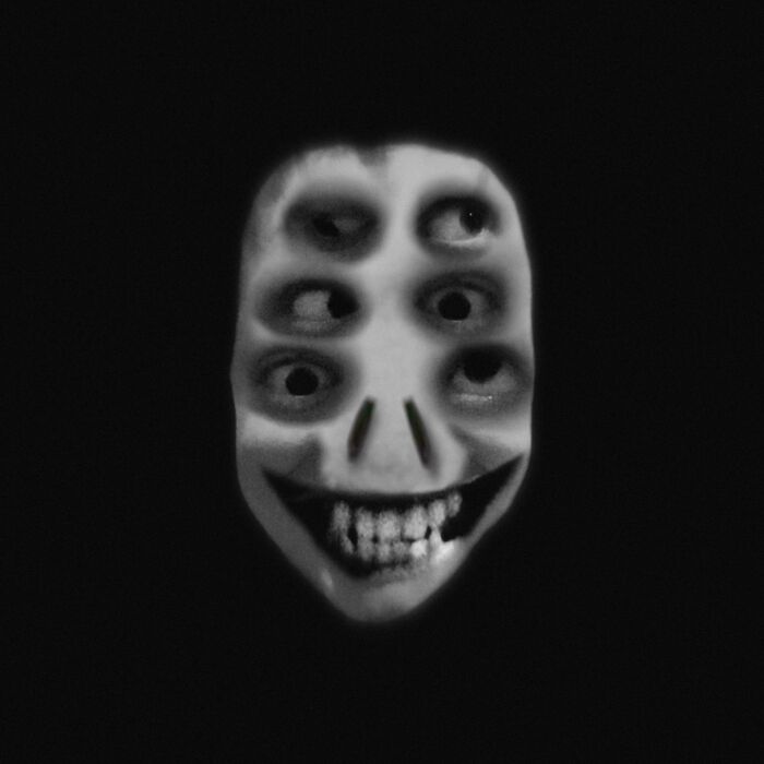 Creepy image of a face with multiple eyes and a wide grin, resembling "Hair of Kids I Babysit".