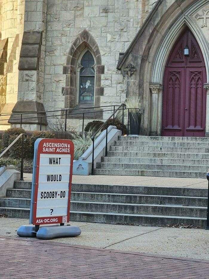 Bizarre and hilarious church sign asking what Scooby-Doo would do displayed outside stone building with red doors.