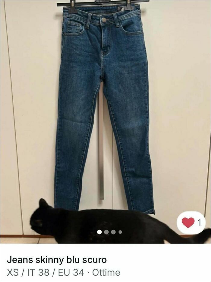 Black cat walking below a pair of skinny dark blue jeans in a Vinted clothing ad, spotlighting cats in ads.