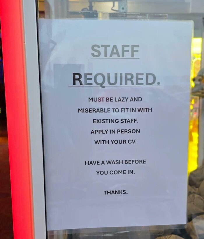 Sign humorously requesting staff to be lazy and miserable to fit in, showcasing bizarre and hilarious signs not seen every day.