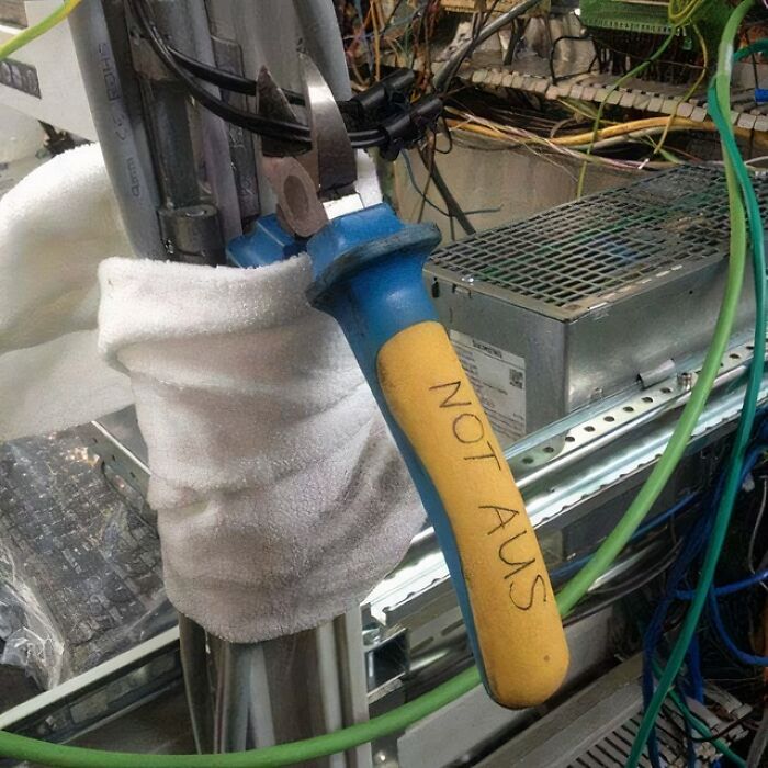 Improvised electrical setup with a towel insulation and a tool handle labeled not AUS demonstrating if it's stupid but it works concept.