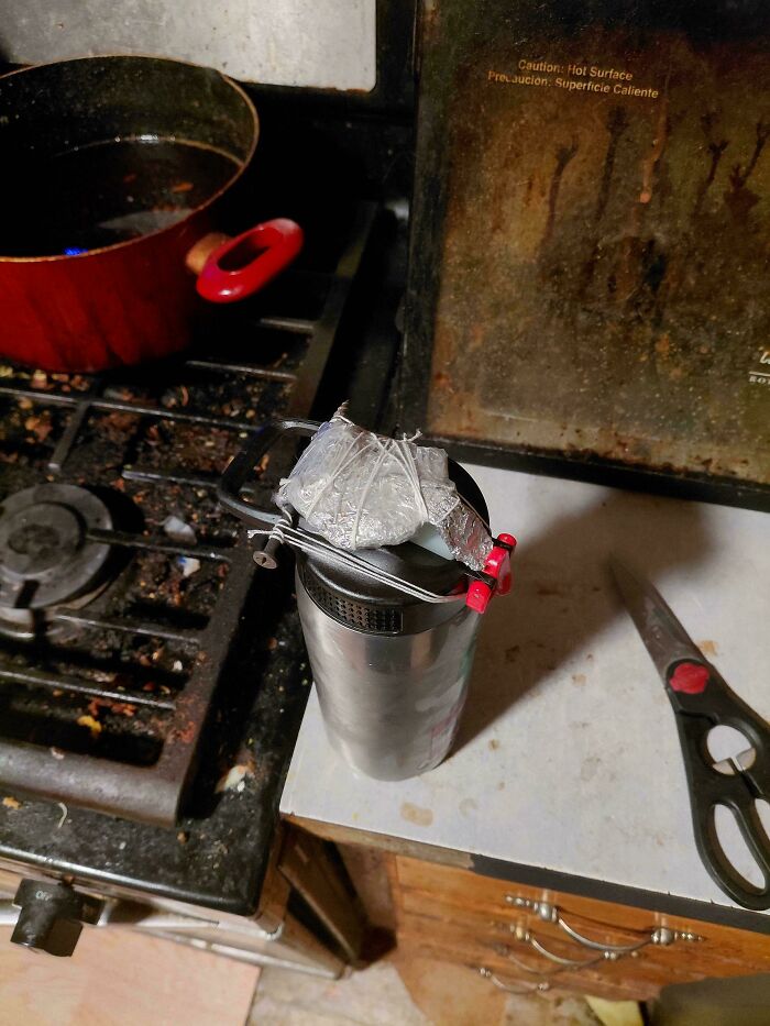 Improvised kitchen setup showing a homemade clamp on a thermos, an example of redneck engineering creativity.