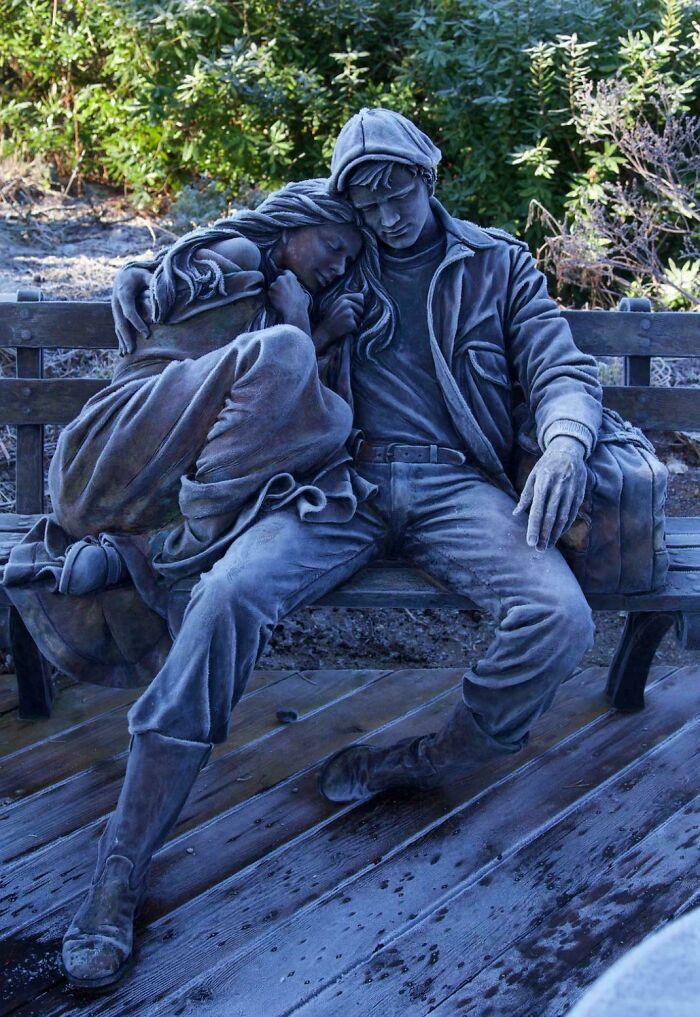 Frozen statue of a couple sitting on a bench, covered in frost, an amazing photo of winter's grip.