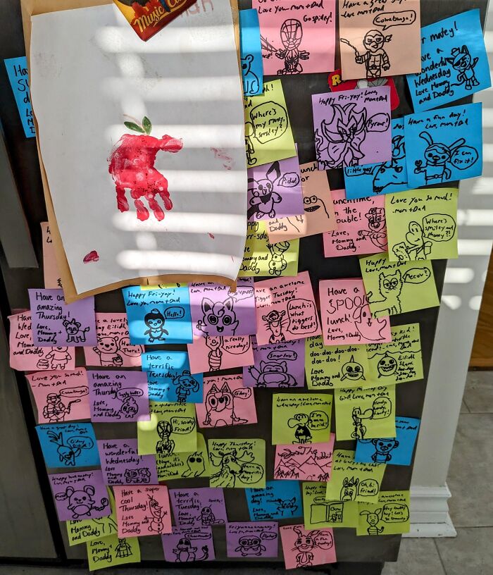 Refrigerator covered with colorful sticky notes featuring creative and amusing parent drawings and messages.