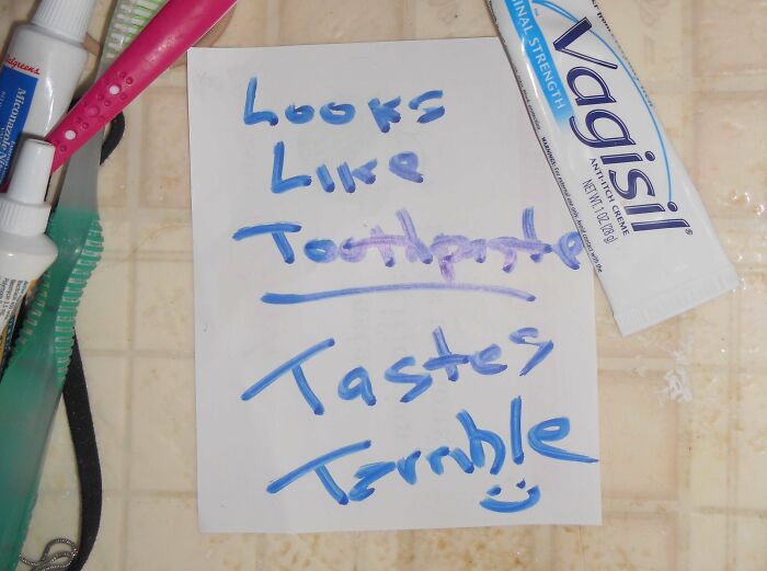Note left by a parent in blue marker saying toothpaste tastes terrible, next to a toothbrush and cream tube on a bathroom counter.