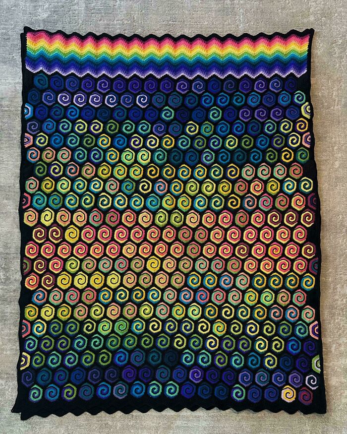 Awesome crocheted blanket with colorful spiral hexagons in a rainbow gradient pattern, showcasing a truly wowing project.