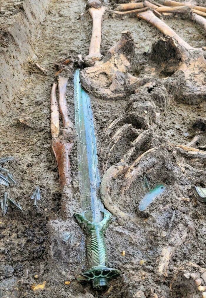 An amazing photo of a skeleton with an ancient sword buried in the dirt. This picture might teach you something new.