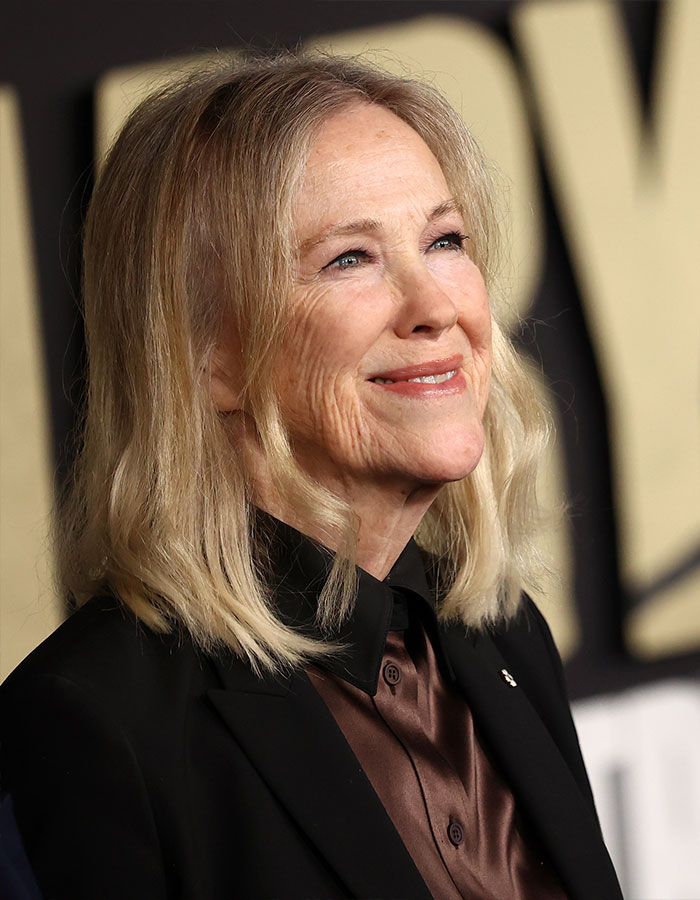 Catherine O'Hara smiling at an event, wearing a black blazer and brown shirt, famous Schitt’s Creek star. Catherine O'Hara smiling at an event, wearing a black blazer and brown shirt, famous Schitt’s Creek star.