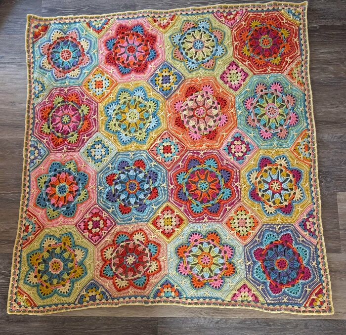 A vibrant crocheted blanket featuring colorful, floral hexagonal and square motifs, an awesome example of crocheted craft.