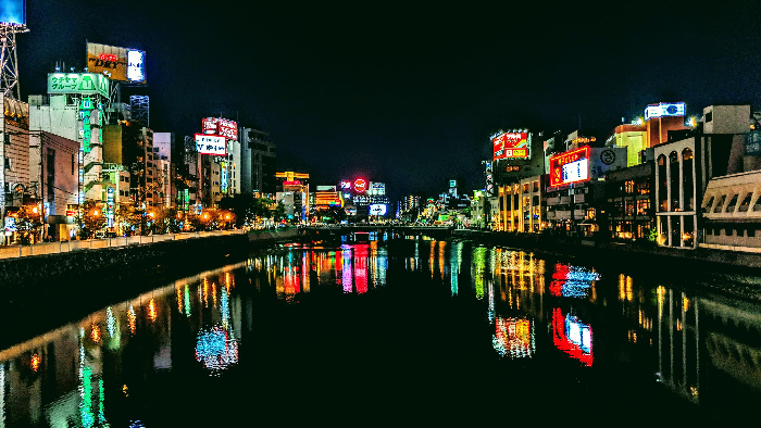 Night cityscape over calm river with colorful reflections, illustrating best countries to raise a family with high child wellbeing.