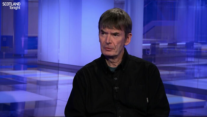 Man in black shirt appearing serious during a televised interview about meeting idols in real life and regret shared online.