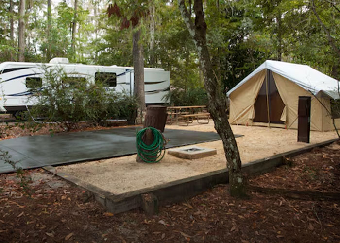 Empty wooded campsite at Disney World with RV, canvas tent, picnic table and coiled hose
