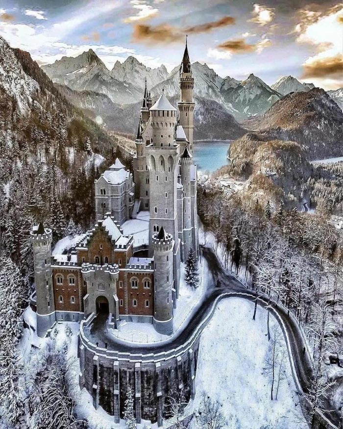 Snow-covered castle surrounded by mountains and forest, illustrating countries that sleep the most in OECD time use data.