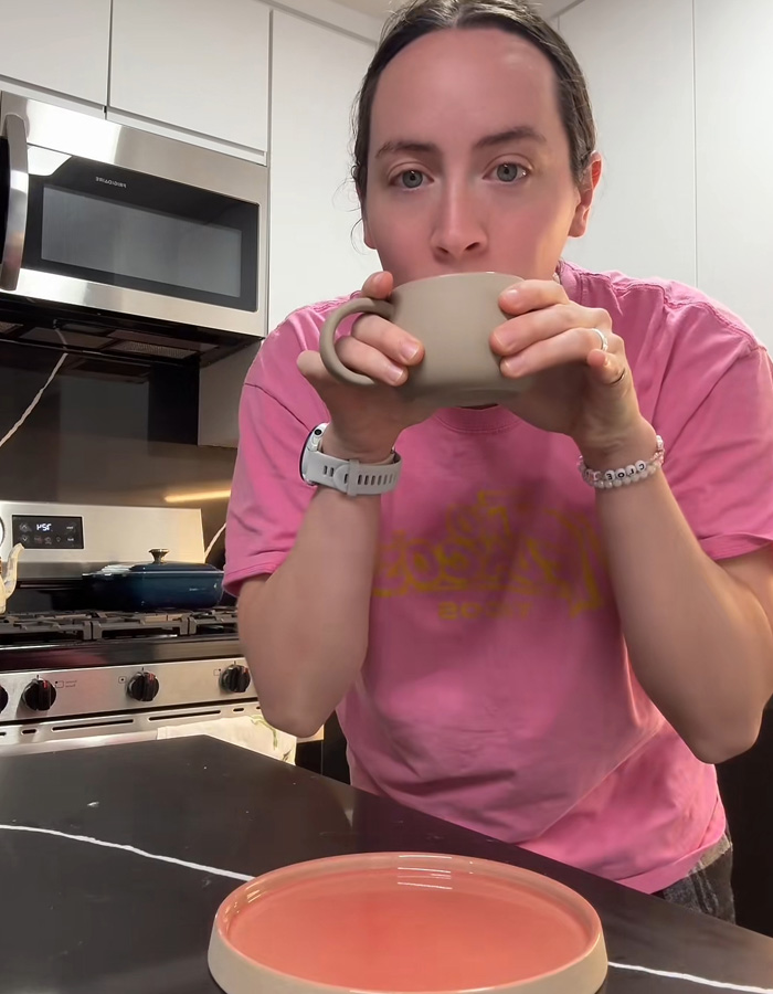 Person in a pink shirt drinking from a mug gift sparking a huge relationship debate online in a modern kitchen setting Person in a pink shirt drinking from a mug gift sparking a huge relationship debate online in a modern kitchen setting