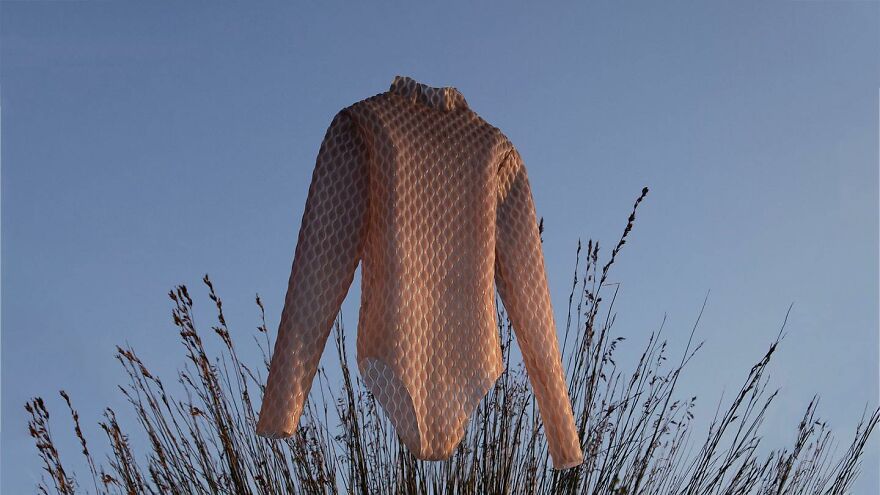 Honeycomb textured bodysuit inspired by biomimicry design, displayed against clear sky and tall grasses outdoors.