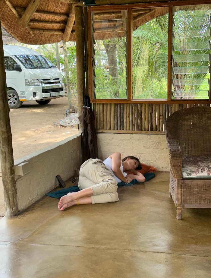 Woman resting on the floor in a rustic setting, illustrating myths vs reality about whether women need more sleep than men.
