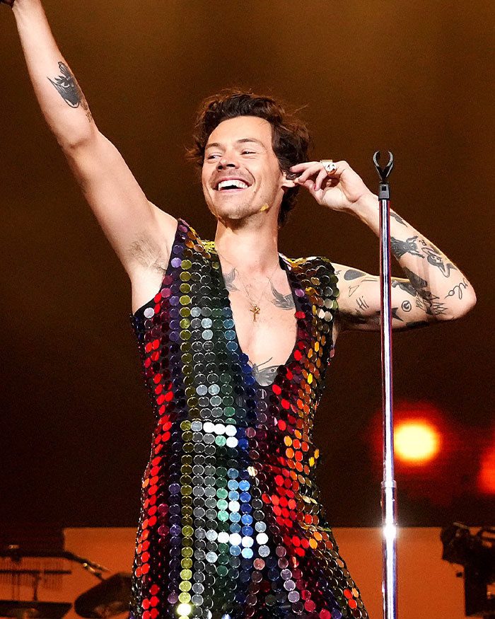 Male singer performing on stage wearing a colorful sequined outfit, embodying the hidden stories in famous songs.