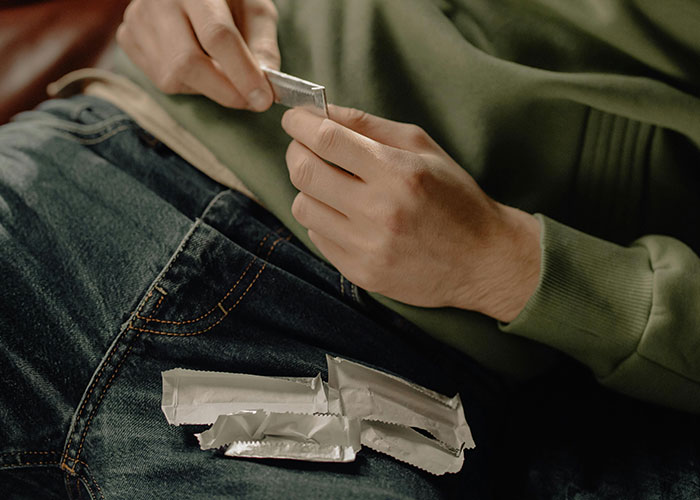 Person rolling a small package with multiple wrapped items on their lap, illustrating secretive revenge acts.