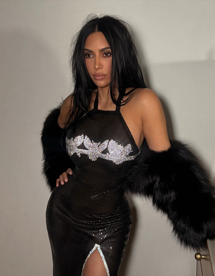 Kim Kardashian posing in black dress with sequins and fur sleeves, linked to viral livestream parenting controversy.
