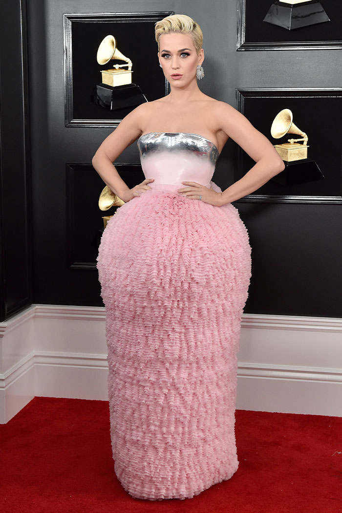 Female celebrity in a metallic and pink textured gown posing on the red carpet at a Grammys event showcasing wild Grammys looks.