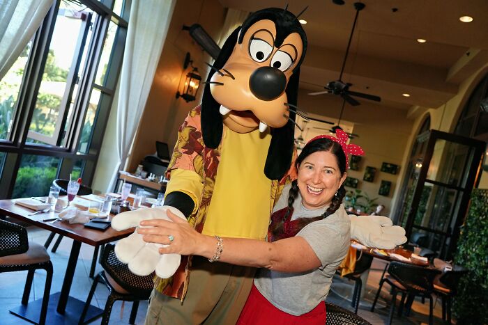 Woman happily hugging Goofy character inside a quiet Central Florida restaurant, capturing beauty and real emotion moments.