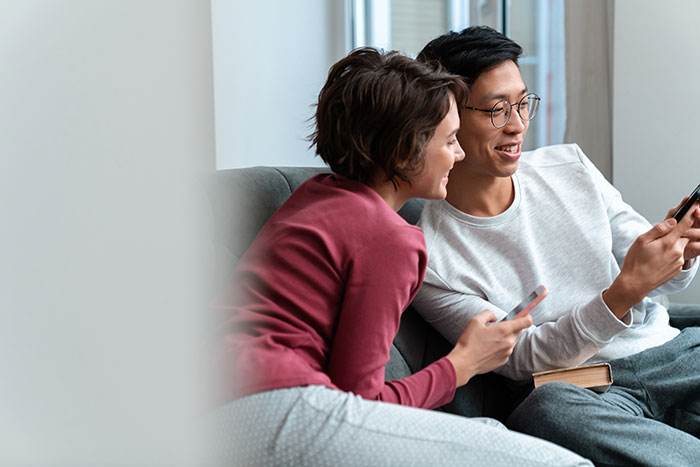 Young dad and kids spending time together, sharing moments on smartphones in a cozy home setting.