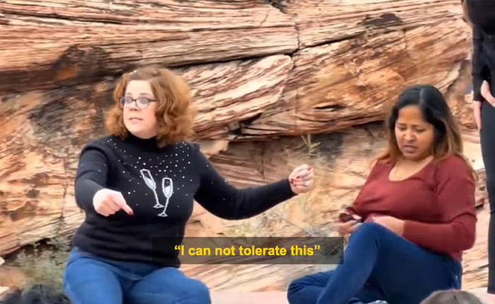 Woman blocking tourist&rsquo;s shot at Red Rock Canyon during viral First Karen of 2026 incident, seated on rocky ground.