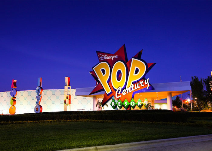 Pop Century Resort entrance sign illuminated at night at Disney World, colorful retro signage and resort driveway