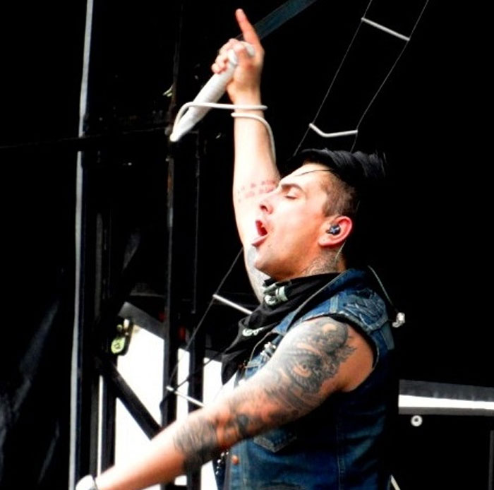 Tattooed male singer passionately performing on stage, representing celebrities whose careers crashed and never recovered.