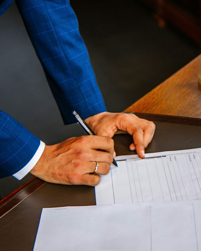Man in blue suit signing legal documents, illustrating father changing gender identity to avoid child support controversy.