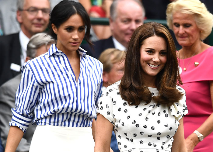 Kate Middleton smiling in a white dress with black polka dots, alongside Meghan Markle in a blue striped shirt.