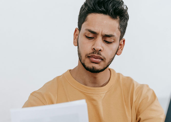 Young man with a focused expression reading a document, illustrating habits neurodivergent people thought were normal