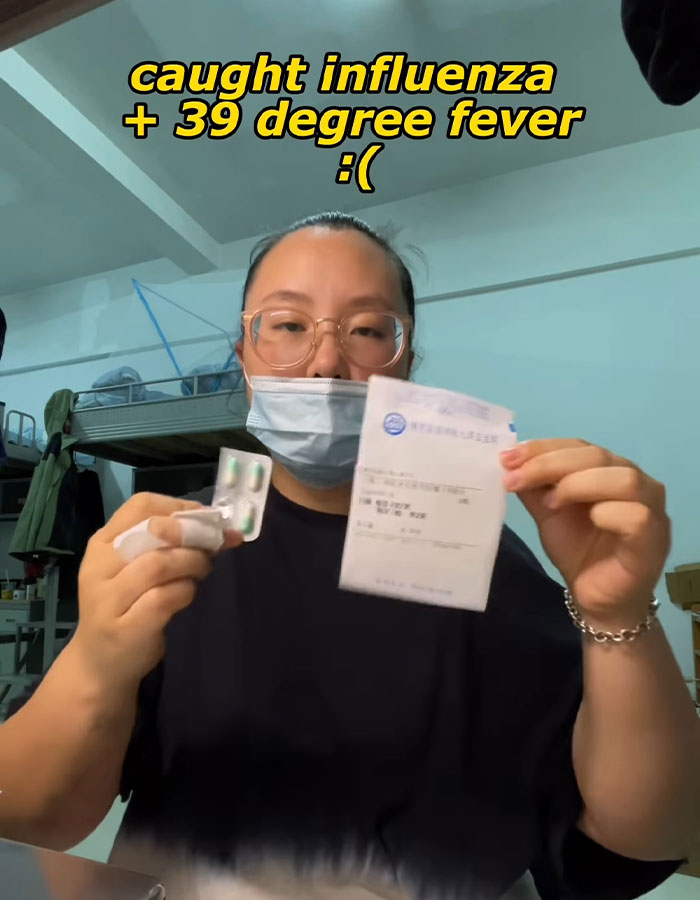 Woman wearing mask holding medication and prescription, highlighting conditions in fat prison during illness.